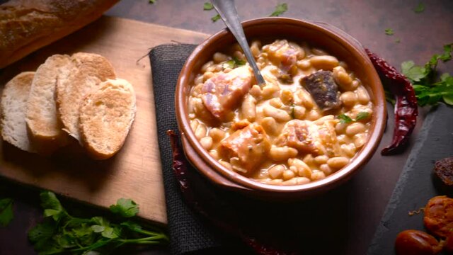 Traditional recipe of beans with chorizo and blood sausage called &ldquo;Fabada Asturiana&rdquo; on a dark table with some ingredients around. Typical Spanish food with &ldquo;compango&rdquo;. 