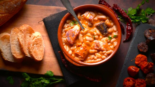 Traditional recipe of beans with chorizo and blood sausage called &ldquo;Fabada Asturiana&rdquo; on a dark table with some ingredients around. Typical Spanish food with &ldquo;compango&rdquo;. 