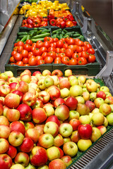 Apples, tomatoes, cucumbers and other vegetables and fruits in boxes on the counter in a market