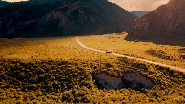 White car drives through narrow road in the mountains. Drone footage