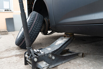 Fototapeta premium Photo of a wheel near a car and a jack.