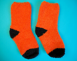 two warm knitted orange and black colors lie side by side on a blue background . top view