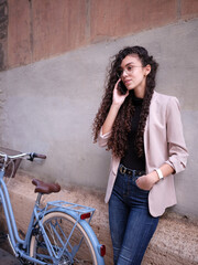 woman standing next to a bike conversing on the telephone