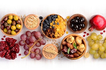 Mix of dried fruits, barley, wheat, olives, pomegranate on wooden table - symbols of judaic holiday Tu Bishvat. Copyspace background.Top view