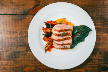 Top view plate with sliced duck steak on wooden table