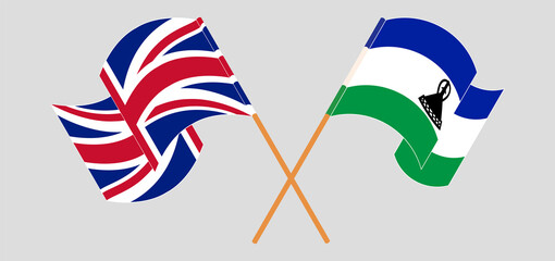 Crossed and waving flags of United Kingdom and Kingdom of Lesotho