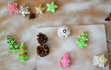 Christmas composition: Christmas cupcakes decorated with icing and surrounded by cinnamon sticks and star anise on a background of powdered sugar