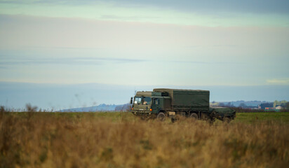 Fototapeta na wymiar british army MAN SV 4x4 vehicle truck with attached trailer driving along a dirt track in action on a military exercise, Salisbury Plain UK
