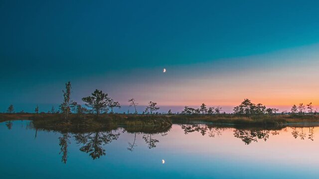 4K Sunset And Moon Rising Above Landscape With Lake Swamp Bog Marsh Wetland Nature At Night Light. TimeLapse Time-Lapse Starry Sky Milky Way Galaxy With Glowing Stars. Starlight Reflections In Water