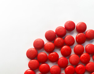 red small wooden balls accumulated in the bottom corner. balls are on white paper and like candy. space for text. 