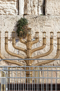 The huge traditional and state-owned menorah in the Western Wall plaza in Jerusalem, a huge gold-colored metal menorah. Against the background of the ancient walls