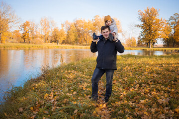 Portrait of a pensive father giving his daughter a piggyback ride on his shoulders and looking up.