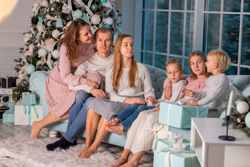 Big happy family with many kids having fun on the sofa near the Christmas tree on Christmas eve