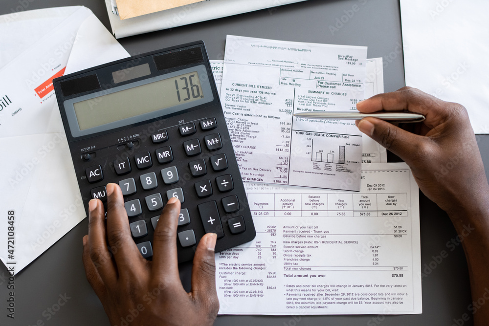 Poster Above view of unrecognizable blackman checking receipts using calculator at table