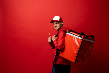 Delivery boy with red thermal bag showing a thumb up. Fast and convenient food delivery service for...