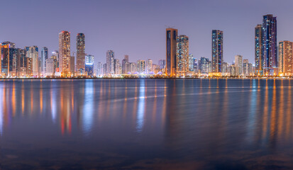 Obraz na płótnie Canvas The tallest towers in the Emirates and their reflection on the lakes at night, Dubai, Sharjah