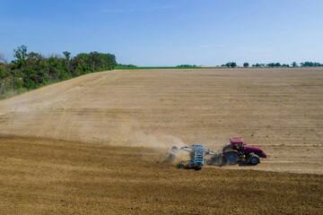 Fototapeta premium The tractor cultivates the land with disk cultivators, after harvesting of grain crops. Before sowing the field.