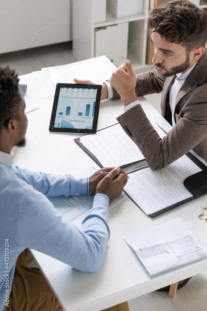 Poster banking specialist in brown jacket showing statistical data to man while telling about bank loan to 