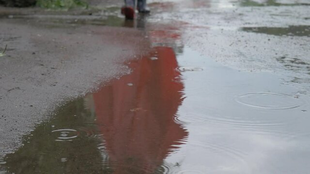 Ni&ntilde;o latino caminando sobre el agua de lluvia.