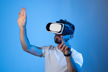 Portrait of man in black t-shirt wearing 3d headset glasses gesturing as if touching something what he doing in virtual reality while playing video games. Metaverse.