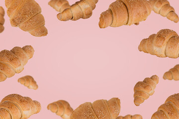 Frame of freshly baked croissants fly in the air isolated on a pastel pink background.
