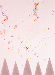 Christmas tree shadows on pastel pink background with multicolored party decoration.  Christmas and new year celebration concept, flat lay composition.