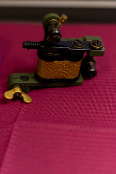 vertical detail image of a professional tattoo machine on a reddish background