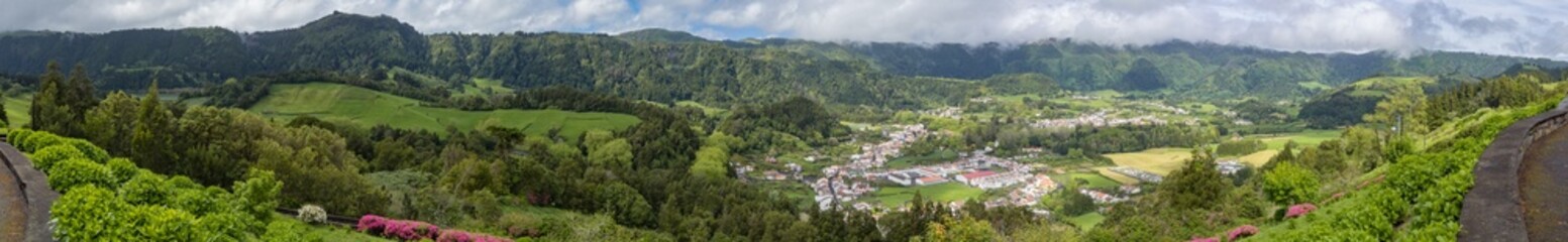 Fototapeta na wymiar Huge panorama landscape of natural place full of trees, mountains and small remote village in country side of sao miguel island, azores, açores