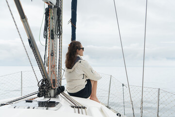 Woman sitting on a sailboat looking at the ocean