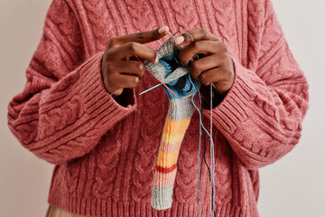 Minimal close up of young African-American woman knitting socks, copy space