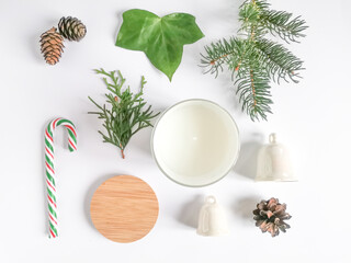 Fototapeta na wymiar Christmas set with aromatic candle, pine cones, candy, bells, green leave and spruce branch on the white background.
