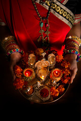 A woman is sari holding pooja plate 