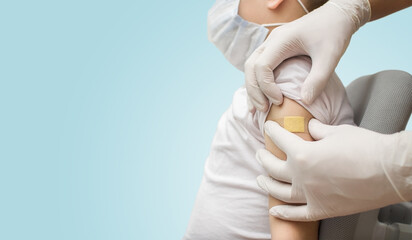 The doctor glues an adhesive plaster on the boy's hand after vaccination. Coronavirus and flu...