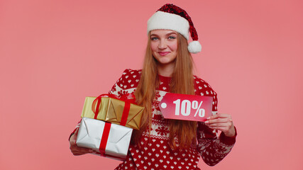 Happy girl in red New Year sweater showing gift box and 10 Percent discount inscriptions banner text. Black Friday. Good holiday low prices for shopping. Pink studio wall background. Merry Christmas