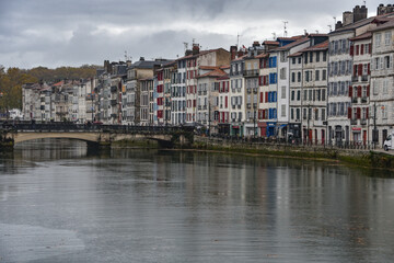 Fototapeta na wymiar BAYONNE, FRANCE - 30 Oct, 2021: Old houses by the river La Nive in the center of Bayonne, Aquitaine, France