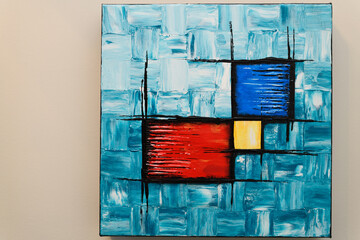 Abstract acrylic painting of turquoise squares with red blue and yellow cubes on square canvas frame