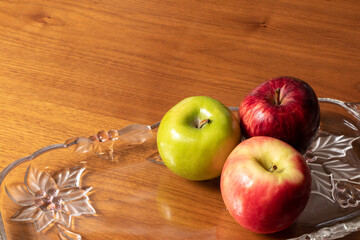 mixture of apples, red and green apples, in transparent glass container on wooden table.