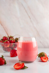 drink in glass and glass of milk cocktail and strawberries forming a splash with natural strawberries in a bowl