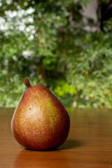 delicious pear on wooden table, blurred green vegetation in the background, close-up photo space for text