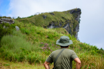 A trekker stands looking at the path on the mountain to travel.