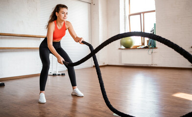 Fototapeta na wymiar Trainer at the fitness club. A confident woman does cardio, an athletic body, holds sports equipment in her hands. Healthy lifestyle and exercise.