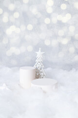 Podiums mok-up for cosmetics in the snow with a christmas tree on a bokeh background vertical format