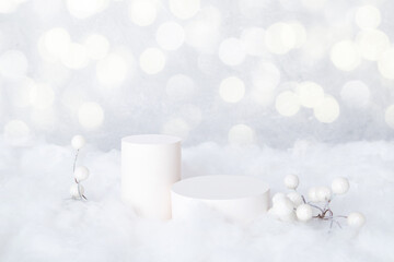 Mock-up podiums for cosmetics in the snow with decorative berries on bokeh background