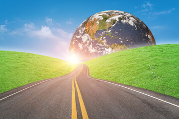 Asphalt road and green grass field forward to globe on sunny day. Elements of this image furnished...