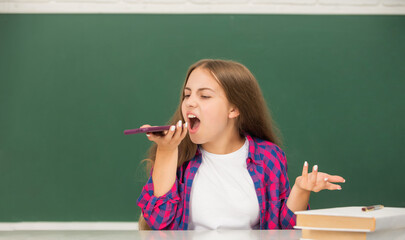 angry child at school talking on phone on blackboard background, phone call