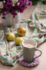 Cup of aromatic coffee, beautiful flowers and bright cloth on wooden table