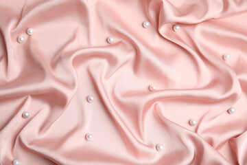 Many beautiful pearls on delicate pink silk, flat lay
