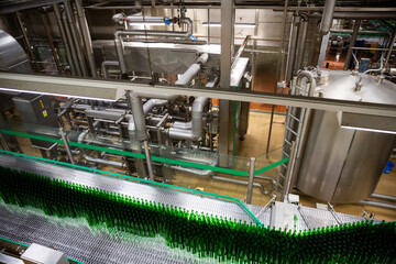 Close up of green glass unlabeled bottles of beer on bottling line
