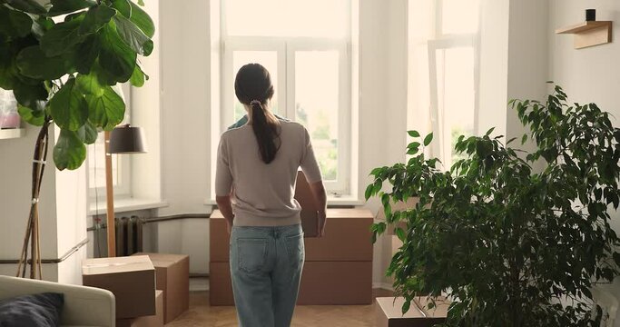 Young family couple move to new house apartment carry packages with furniture stuff together. Happy spouses furnish purchased flat at relocation day give high five putting box with belongings on floor