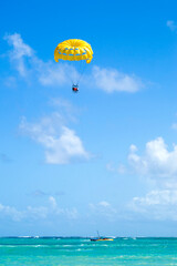 Yellow parasailing  with 3 people towed at beach in Punta Cana